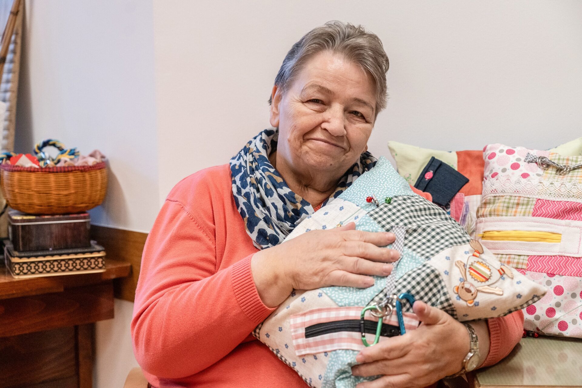 Bewohnerin im Pflegeheim hält ein selbstgemachtes Patchwork-Kissen in den Händen.