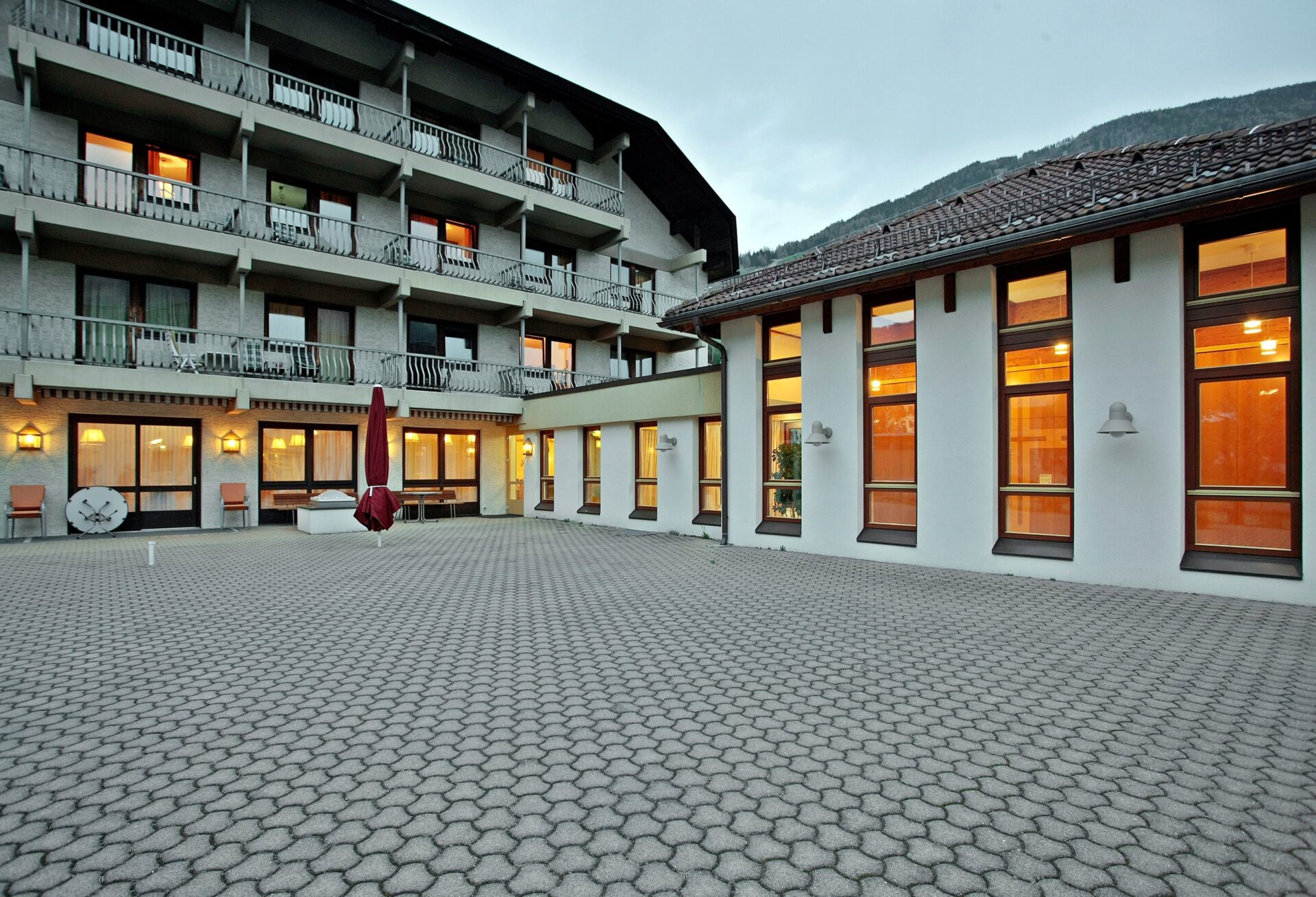 Innenhof eines Gebäudekomplexes mit mehrstöckigem Wohnbau, großen Fenstern und gepflasterter Fläche.