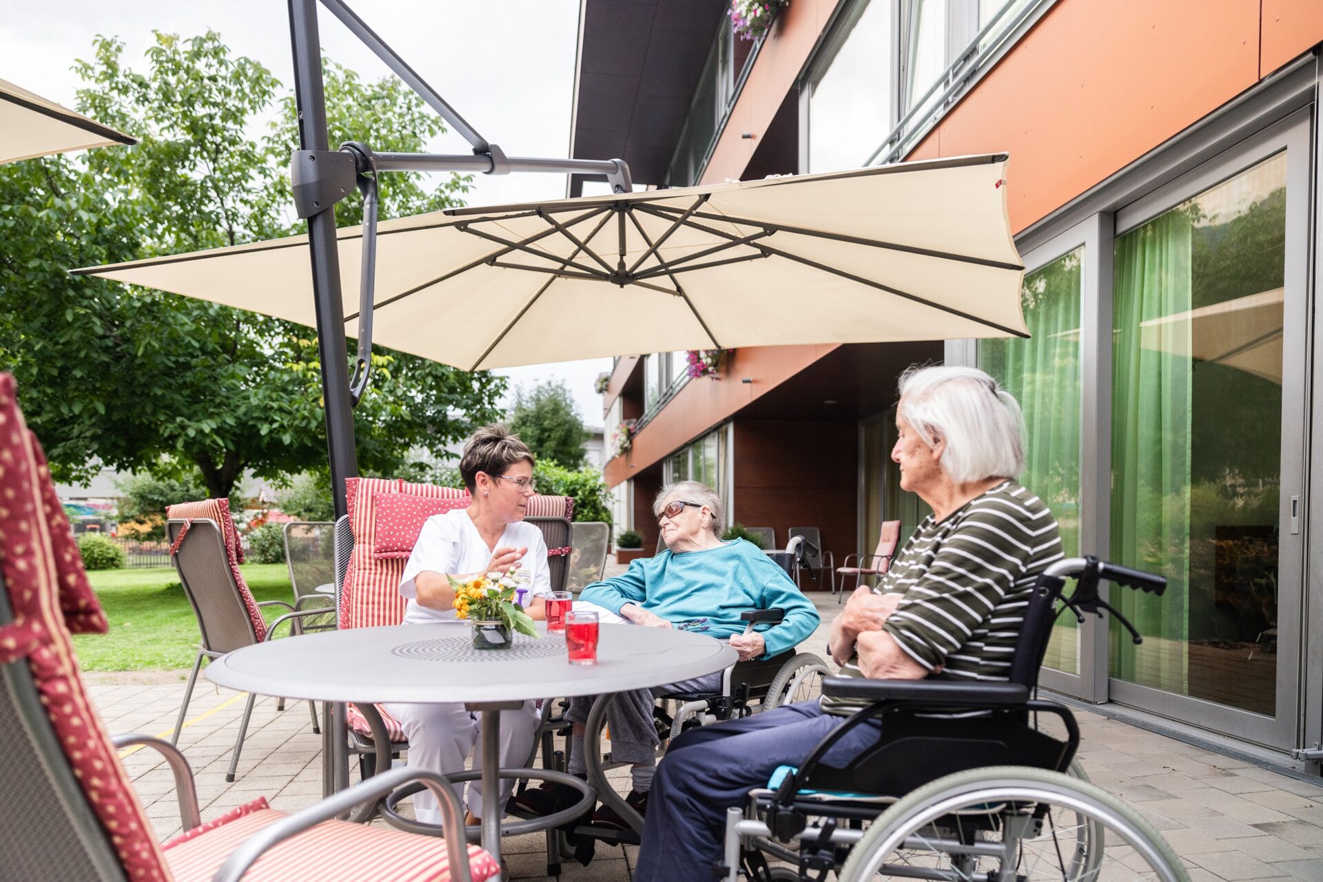 Bewohnerinnen und Bewohner im Gespräch mit einer Pflegefachkraft auf der Terrasse des Wohn- und Pflegeheims Sillian.